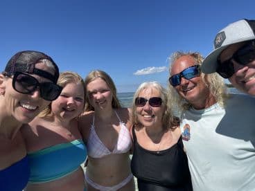A joyful group of family members poses for a selfie on the beach, capturing a fun day in the sun — perfect for family vacations and beach outings.
