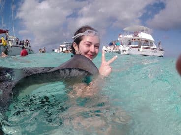A joyful swimmer interacts with a stingray in crystal-clear waters, capturing the thrill of wildlife encounters during a memorable aquatic adventure.