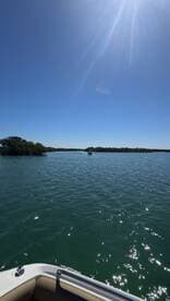 A scenic view of a boat navigating through tranquil waters, surrounded by lush greenery under a clear blue sky, perfect for exploring nature.