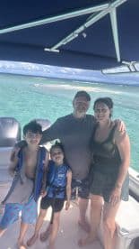 A joyful family poses together on a boat, surrounded by stunning ocean views — a perfect moment capturing family fun on the water.