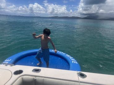 A young boy enjoys splashing around in an inflatable pool on a boat, capturing the joy of summer water activities and family fun.