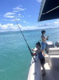 Two children enjoy a fishing adventure on a boat, surrounded by clear blue waters — a perfect family outing on the ocean.