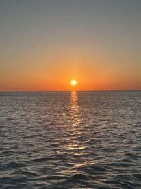 A stunning sunset over calm waters, creating a picturesque scene perfect for evening boat cruises.