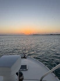 A serene view from the bow of a boat at sunset, showcasing the tranquil waters and the horizon — perfect for peaceful evening cruises.
