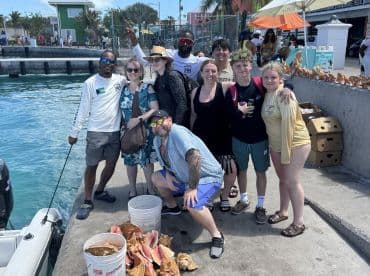 A lively group of friends poses for a photo at the dock, celebrating their day on the water with conch shells in the foreground — a perfect snapshot of fun and camaraderie.
