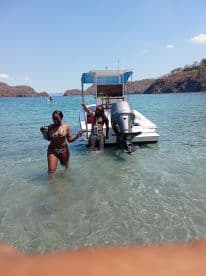 Two friends enjoy a sunny day at the beach, wading in clear waters next to their boat — a perfect setting for fun and relaxation.