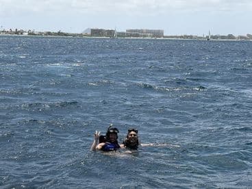 A couple enjoys snorkeling in the ocean, showcasing a fun and adventurous day on the water. The vibrant scenery and clear waters make for an unforgettable experience.