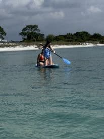 Two friends enjoy paddleboarding in calm waters, showcasing a fun and active day on the water.