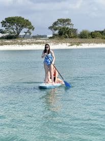 Two friends enjoy paddleboarding in clear waters, showcasing a fun beach day filled with adventure and relaxation.