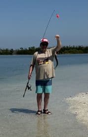 A man proudly displays his catch while fishing at the beach, showcasing the thrill of a successful day on the water.