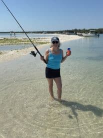 A woman enjoys a day of fishing at a picturesque sandbar, showcasing the perfect blend of relaxation and adventure on the water.