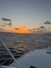 A serene sunset view from the bow of a boat, showcasing the tranquil waters and the fading light — perfect for evening cruises.