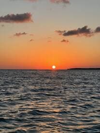 A stunning sunset over the ocean, casting vibrant colors across the water — a perfect backdrop for evening boat cruises.