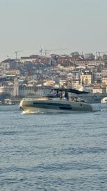 A sleek boat navigates the waters with a vibrant cityscape in the background, showcasing a lively atmosphere perfect for exploring coastal destinations.
