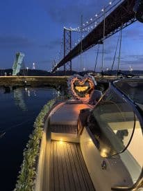 A beautifully decorated boat with a 'Marry Me' sign, set against the backdrop of a stunning bridge at night — perfect for romantic proposals on the water.