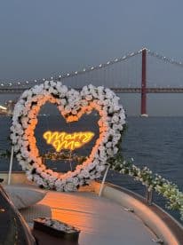 A beautifully decorated boat featuring a 'Marry Me' neon sign surrounded by roses, set against the backdrop of a stunning bridge — an ideal romantic setting for proposals and special celebrations.