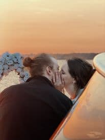 A couple shares a romantic kiss at sunset aboard a boat, creating a perfect backdrop for special moments and celebrations on the water.