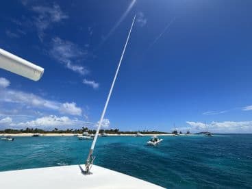 A picturesque view of turquoise waters and a sandy beach, with several boats anchored nearby, showcasing a perfect day on the water.