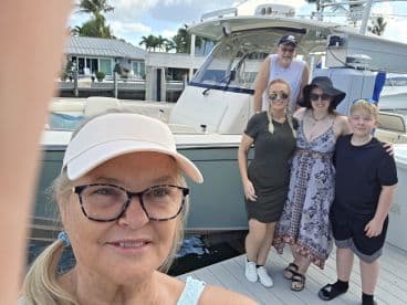 A cheerful family poses for a selfie on the dock beside their boat, capturing a memorable moment together — perfect for family outings and celebrations on the water.