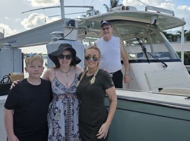 A cheerful family poses together on the deck of a boat, capturing a memorable moment before their adventure on the water.