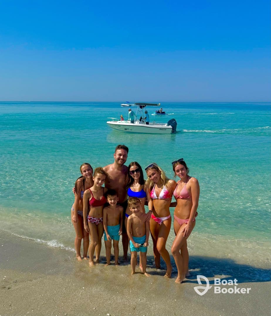 A joyful family poses together on the beach with a boat in the background, capturing a perfect day of fun in the sun and water activities.