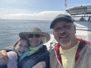 A joyful family selfie on a boat, capturing smiles and togetherness against the backdrop of a serene ocean — perfect for memorable family outings.