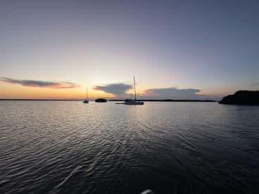 A serene sunset view featuring a sailboat docked in calm waters, perfect for capturing the tranquility of evening boat outings.
