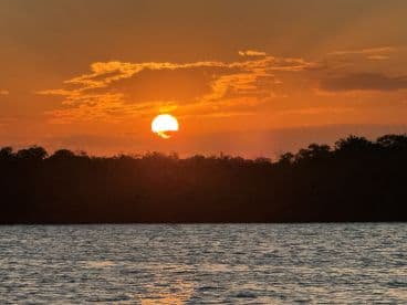 A stunning sunset casts a warm glow over the water, creating a picturesque scene perfect for evening boat trips or romantic getaways.