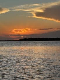 A stunning sunset over calm waters, creating a picturesque scene perfect for evening boat cruises or relaxation by the shore.