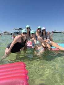 A lively group of friends enjoys a fun day in the water, celebrating with drinks and laughter — the perfect beach party atmosphere.