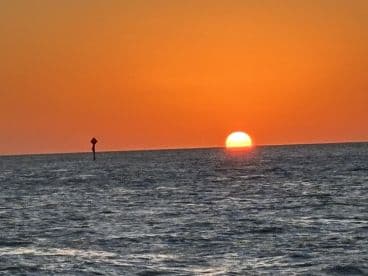 A stunning sunset over the ocean, casting vibrant orange hues across the sky — a perfect backdrop for evening boat trips and romantic getaways.