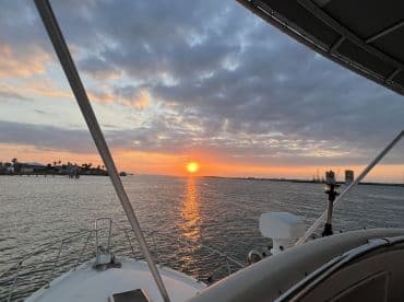 A serene sunset view from the bow of a boat, showcasing the tranquil waters and distant shoreline, perfect for evening cruises.
