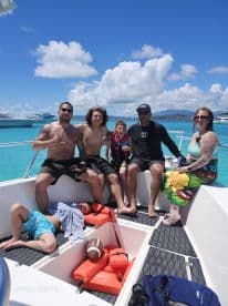 A lively group enjoys a day on the water, showcasing family fun aboard a boat with beautiful turquoise waters in the background.