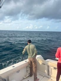 A person fishing from the deck of a boat, enjoying a day on the ocean — a perfect scene for fishing enthusiasts and adventure seekers.