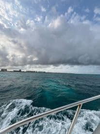 A scenic view from a boat underway, showcasing the vibrant turquoise waters and dramatic cloud formations above, perfect for capturing the essence of a day on the water.