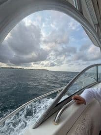A scenic view from the deck of a boat, showcasing the ocean and distant land, with a hand gripping the railing — perfect for capturing the essence of a boating adventure.