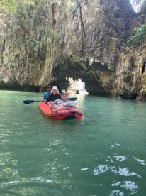 A group enjoys an adventurous kayaking experience through a stunning cave, surrounded by lush greenery and crystal-clear waters — perfect for exploration and outdoor fun.