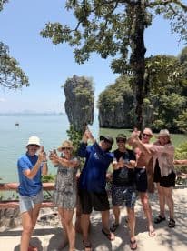 A lively group poses playfully against a stunning island backdrop, capturing the essence of adventure and fun during their boating trip.