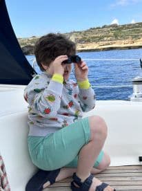 A young boy uses binoculars to explore the scenic views from a boat, capturing the essence of adventure on the water.