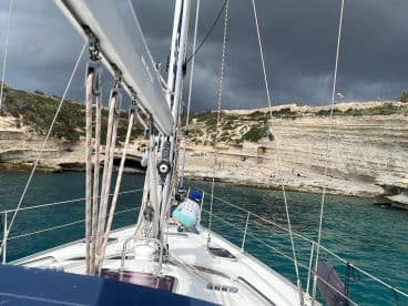 A scenic view from a sailboat approaching a beach with people enjoying the shoreline — perfect for a day of sailing and exploration.