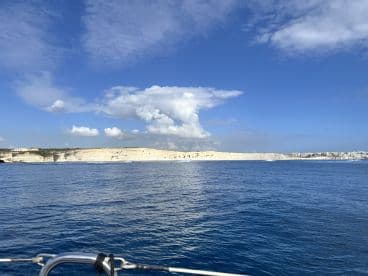 A stunning view of a coastline with dramatic cliffs and clear blue skies, perfect for capturing the beauty of a day on the water.