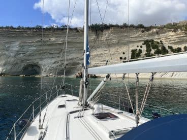 A serene view of a sailboat anchored near stunning cliffs, showcasing the vessel's structure against a picturesque backdrop of nature.
