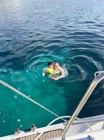A joyful moment captured as a woman and a child swim together in crystal-clear waters, showcasing the fun of family adventures on the water.