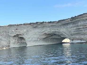 A stunning view of a natural rock arch along the coastline, showcasing the beauty of the landscape and clear waters — perfect for sightseeing adventures.