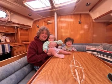 A cozy cabin interior featuring a father with two children, showcasing the inviting atmosphere of a boat's living space.