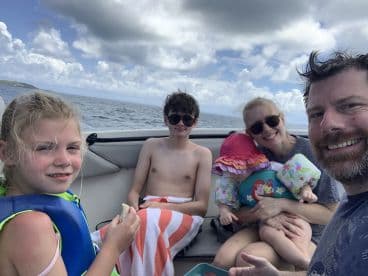 A joyful family enjoys a day on the boat, capturing fun moments together in the sun — perfect for summer adventures and family outings.