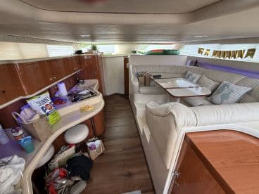 Interior view of a boat's cabin featuring a cozy seating area and dining space, perfect for relaxing and enjoying meals while on the water.