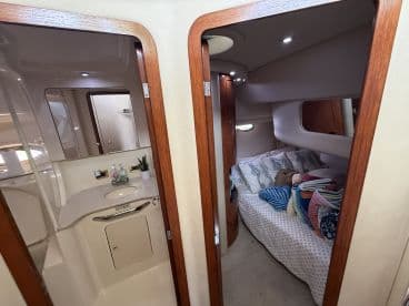 A cozy interior view of a boat cabin featuring a comfortable sleeping area and a well-equipped bathroom, perfect for relaxing on overnight trips.