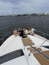 A lively group of friends enjoys a day on the water, celebrating together on the bow of a boat — perfect for memorable outings and gatherings.