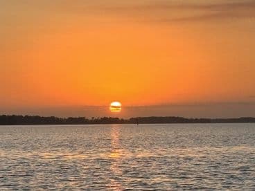 A stunning sunset over calm waters, creating a picturesque scene perfect for evening boat cruises or relaxation by the shore.